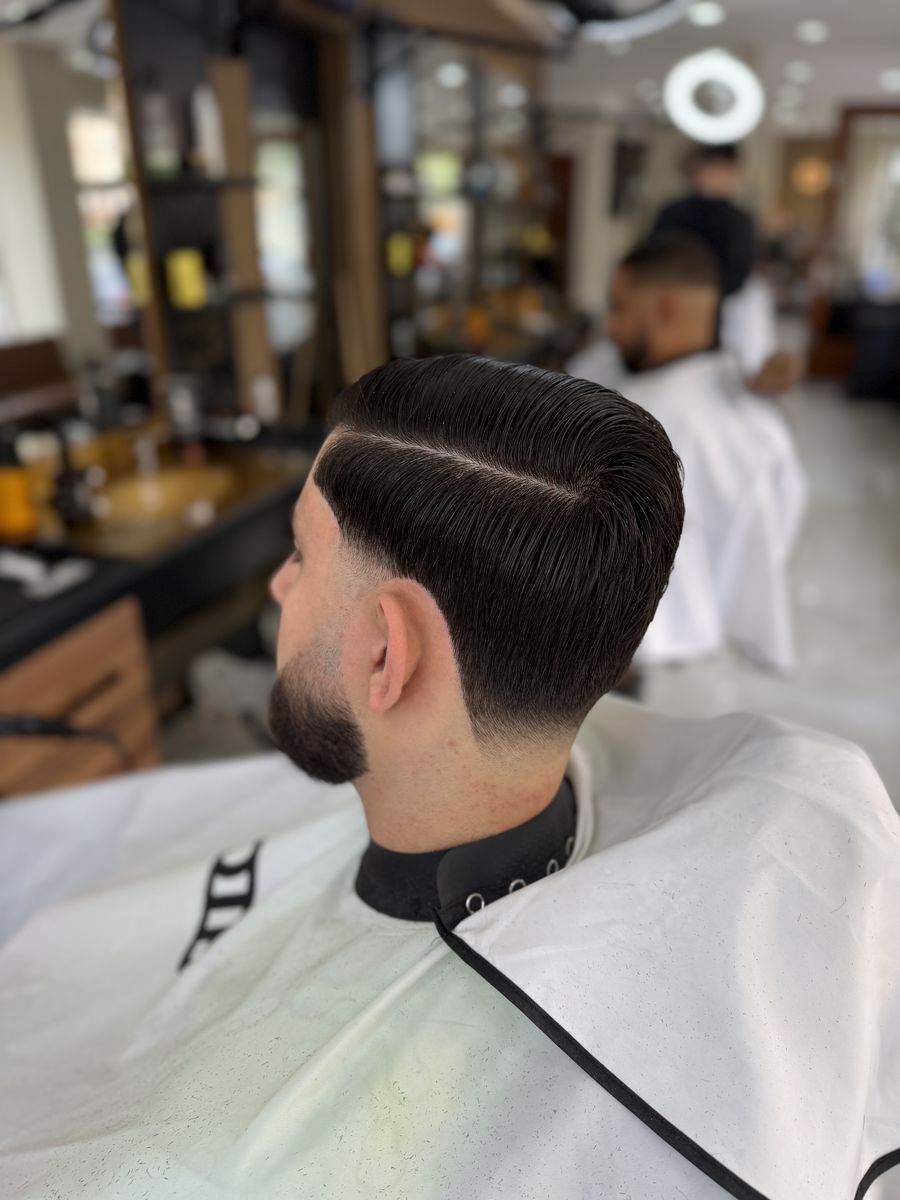 Side part with low fade, combed back at OTB's Barberhouse